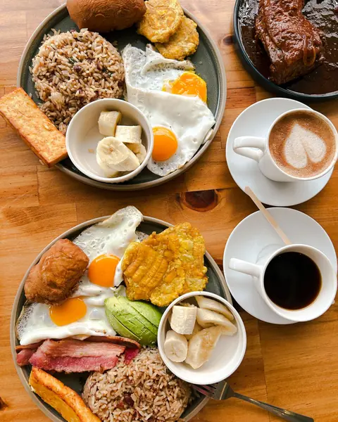 Desayuno típico servido: gallo pinto, huevo frito, plátano maduro y café.