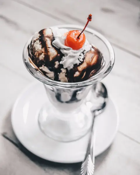 Copa de helado con sirope de chocolate y cereza.