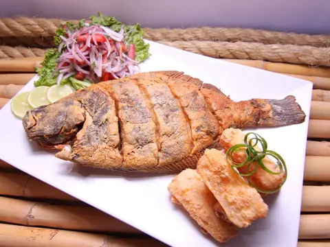 Pescado entero frito con patacones, limón y ensalada.