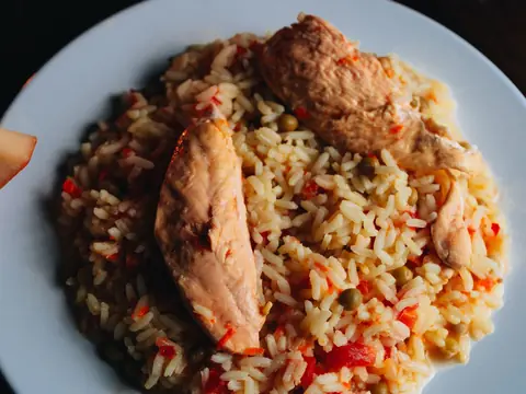 Arroz con pollo y chile dulce servido en plato blanco.